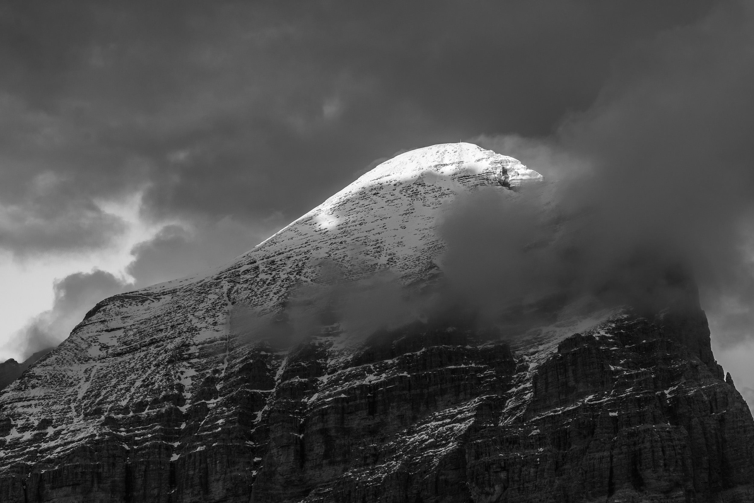 Fotografia in bianco e nero della Tofana di Rozes in ombra con cima innevata e illuminata dal sole.