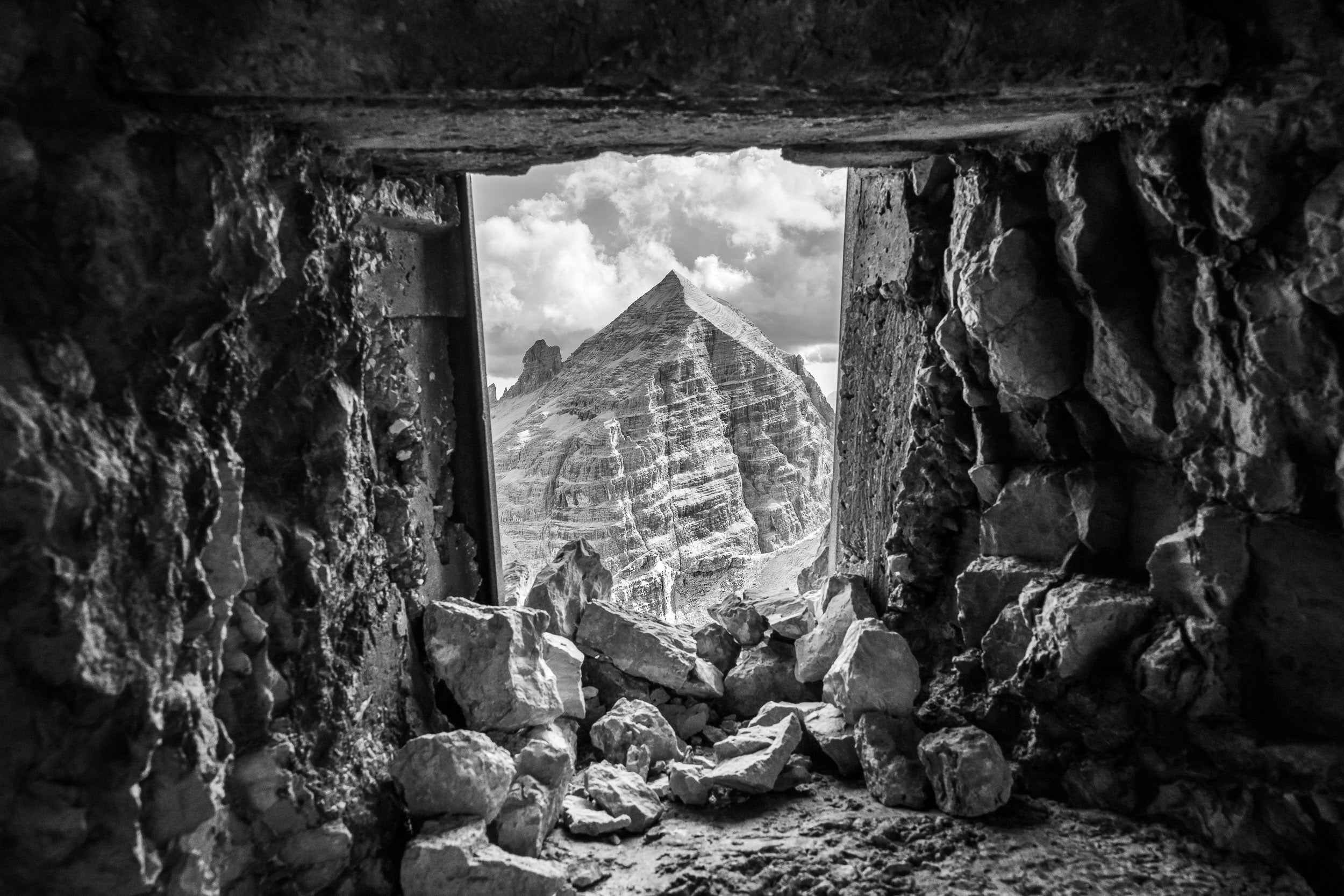 Fotografia in bianco e nero della Tofana di Rozes vista attraverso una postazione militare della Grande Guerra