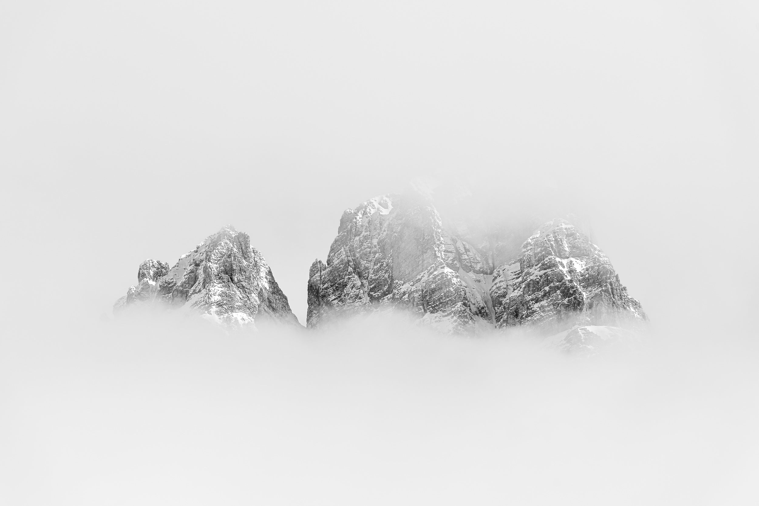 Fotografia invernale in bianco e nero del MOnte Cristallo che emerge dalla nebbia