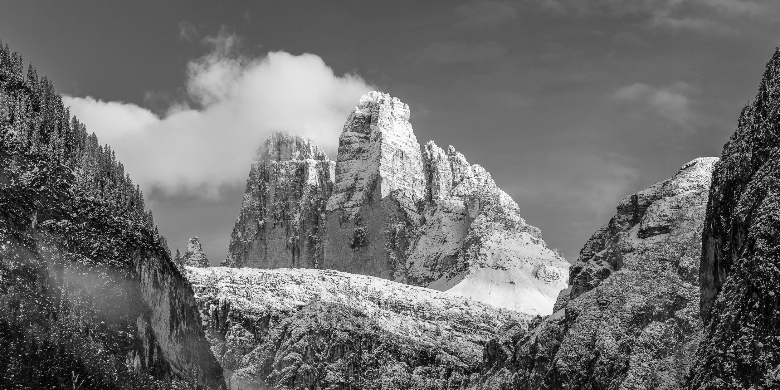 Fotografia invernale delle Tre Cime di Lavaredo con nuvola soffiata dai venti sulle cime.